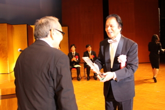 市民会館大ホールで表彰される岸本さんの写真