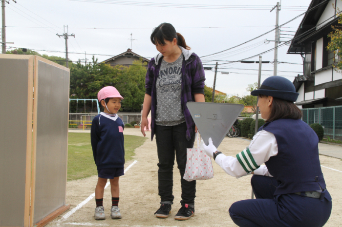 (写真)歩行実習で止まれの標識を習う親子