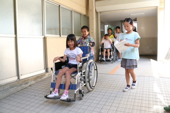 子どもが車椅子でスロープを降りる様子の写真