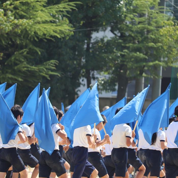 運動会の旗を持って歩く小学生の写真