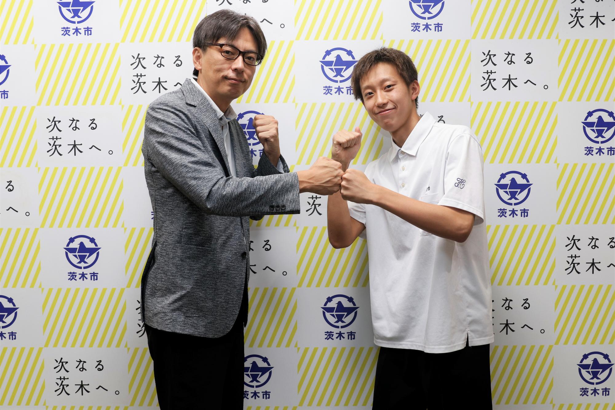 ガッツポーズし、グータッチをする、さくらだこうたさんと、市長の写真