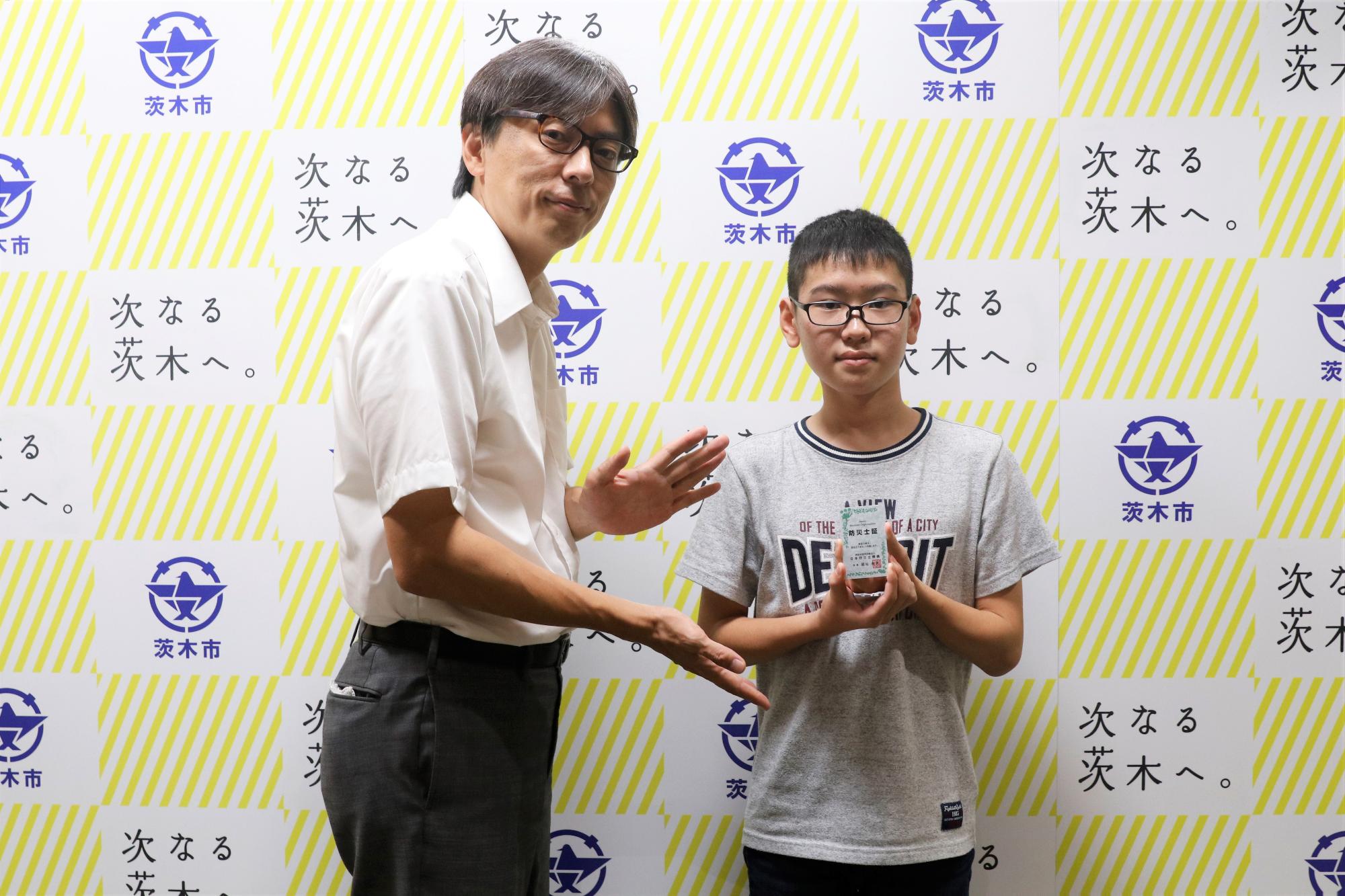 資格証明書を持つ、ひらまつりょうたさんと市長の写真