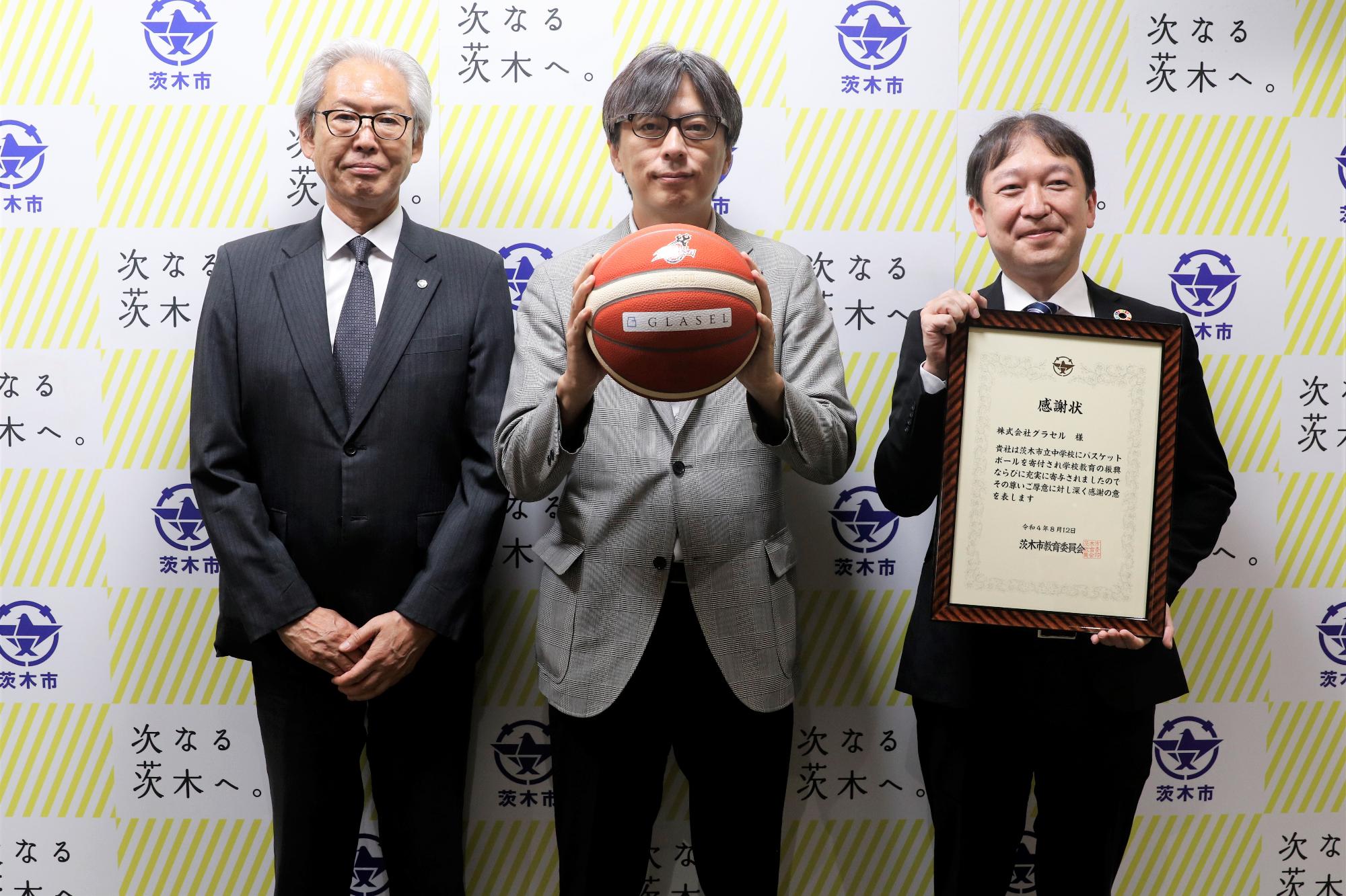 感謝状を持つ、たにむら様とバスケットボールを持つ市長、おかだ教育長の写真