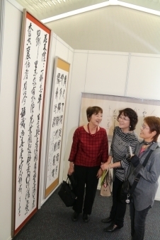 展示されている書を見る女性三人の写真