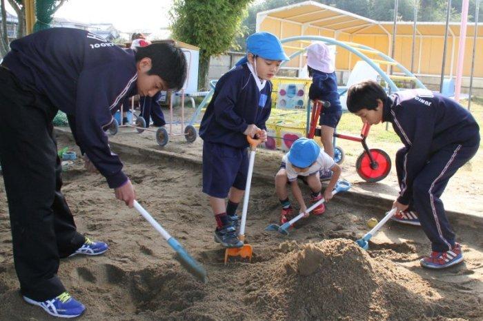 園児たちと砂場で遊ぶ中学生