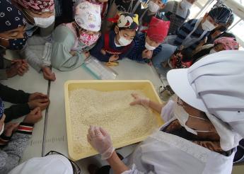 見山の郷のスタッフさんが麹と塩、大豆を混ぜていくのを興味深げに見る児童たち