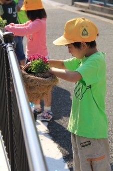 子供が花の植え替えをしている写真