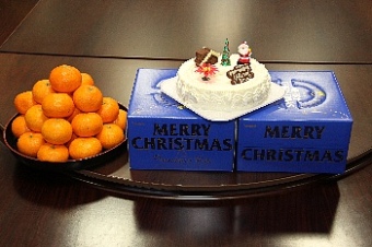 クリスマスケーキとお盆に山積みのみかんが並べられた写真