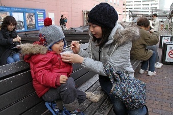 子どもに非常食の試食をさせる母親の写真