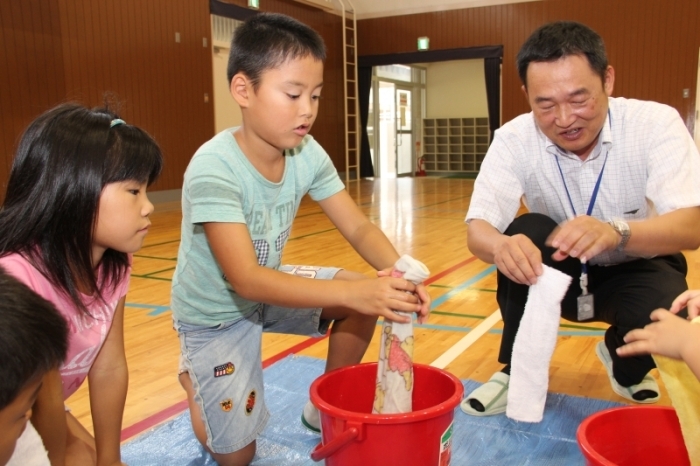 雑巾しぼりに挑戦する児童ら