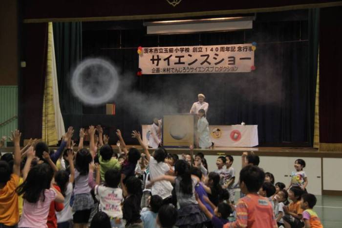 (写真)巨大空気砲からの煙を見る児童ら