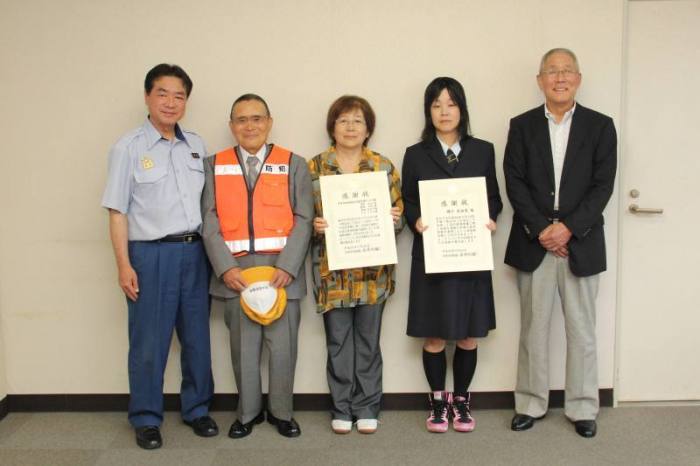 表彰状を手にする磯竹さんと茨木防犯協会玉櫛支部パトロール隊の皆さん