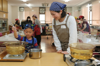 お団子を茹でる子どもと、見守る母親の写真