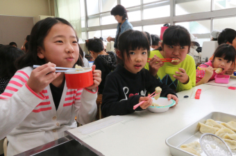 水餃子を食べる児童らの画像