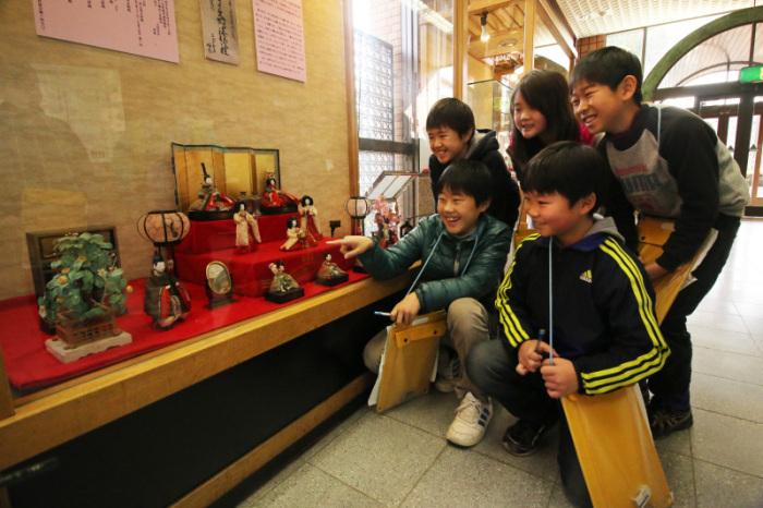 ひな飾りの展示を見る児童らの画像