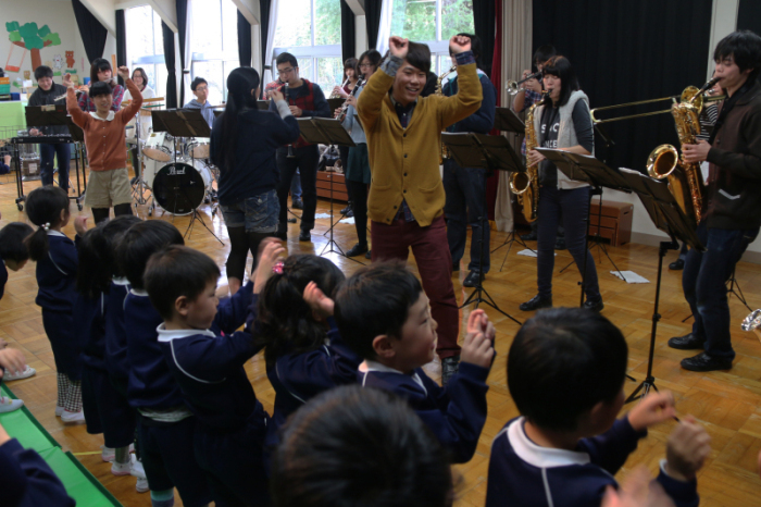 演奏する学生と踊る園児の画像