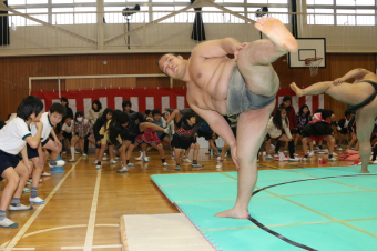 力士と一緒にまた割りをする児童たちの画像