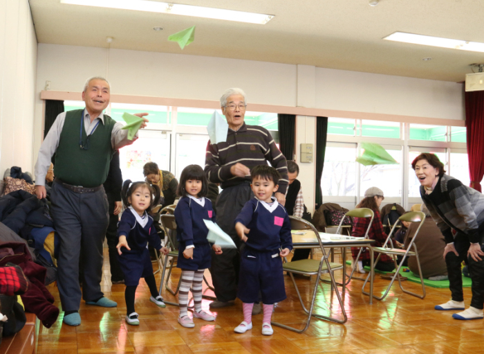 紙飛行機を飛ばす園児と会員の写真