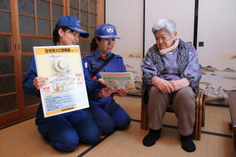 防火訪問で、高齢者に住宅用火災警報器の説明をする消防職員