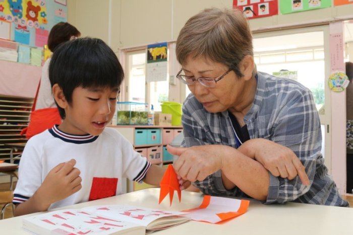 おばあちゃんと折り紙を折る園児の写真