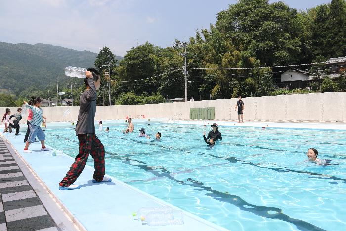 溺れている人に向かってペットボトルを投げる練習をする児童