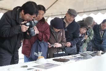 出土した土器などの写真を撮る市民