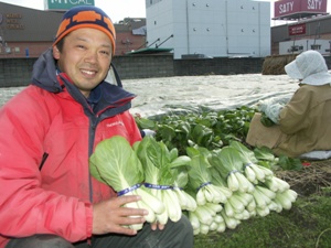 収穫したしろなを持って笑顔を向ける早川訓男さんの写真