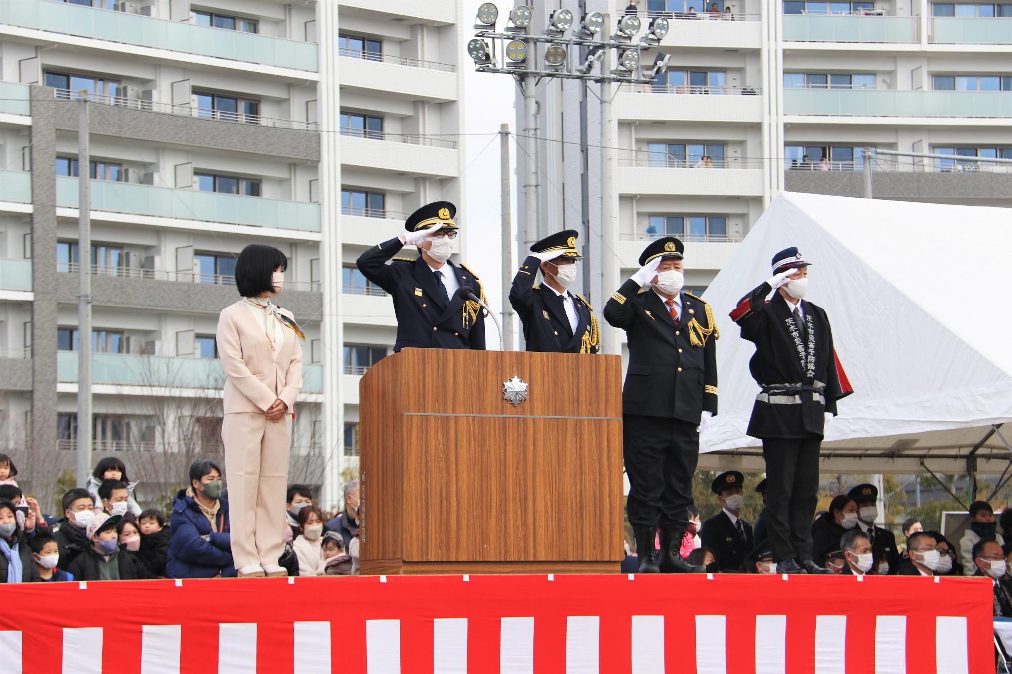 入場分列行進を市閲する、おおの議長、市長、いぬい消防長、にしむら消防団長、まえの茨木市災害予防協会会長の写真