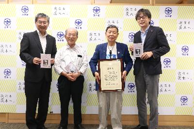 感謝状をもったたなべまさおさんと協力者のやさきてるよしさんが、市長、議長と並んでいる写真