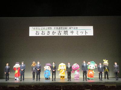 舞台で各市市長と並ぶ市長の写真