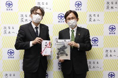 ベビーカーの写真を持つ大阪ガス様と目録を持つ市長の写真
