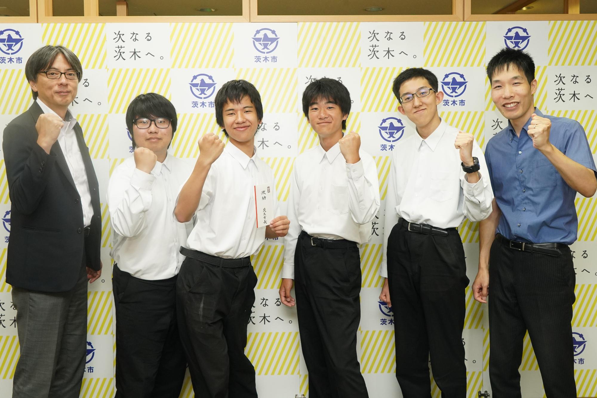 ガッツポーズをする選手、関係者と市長の写真