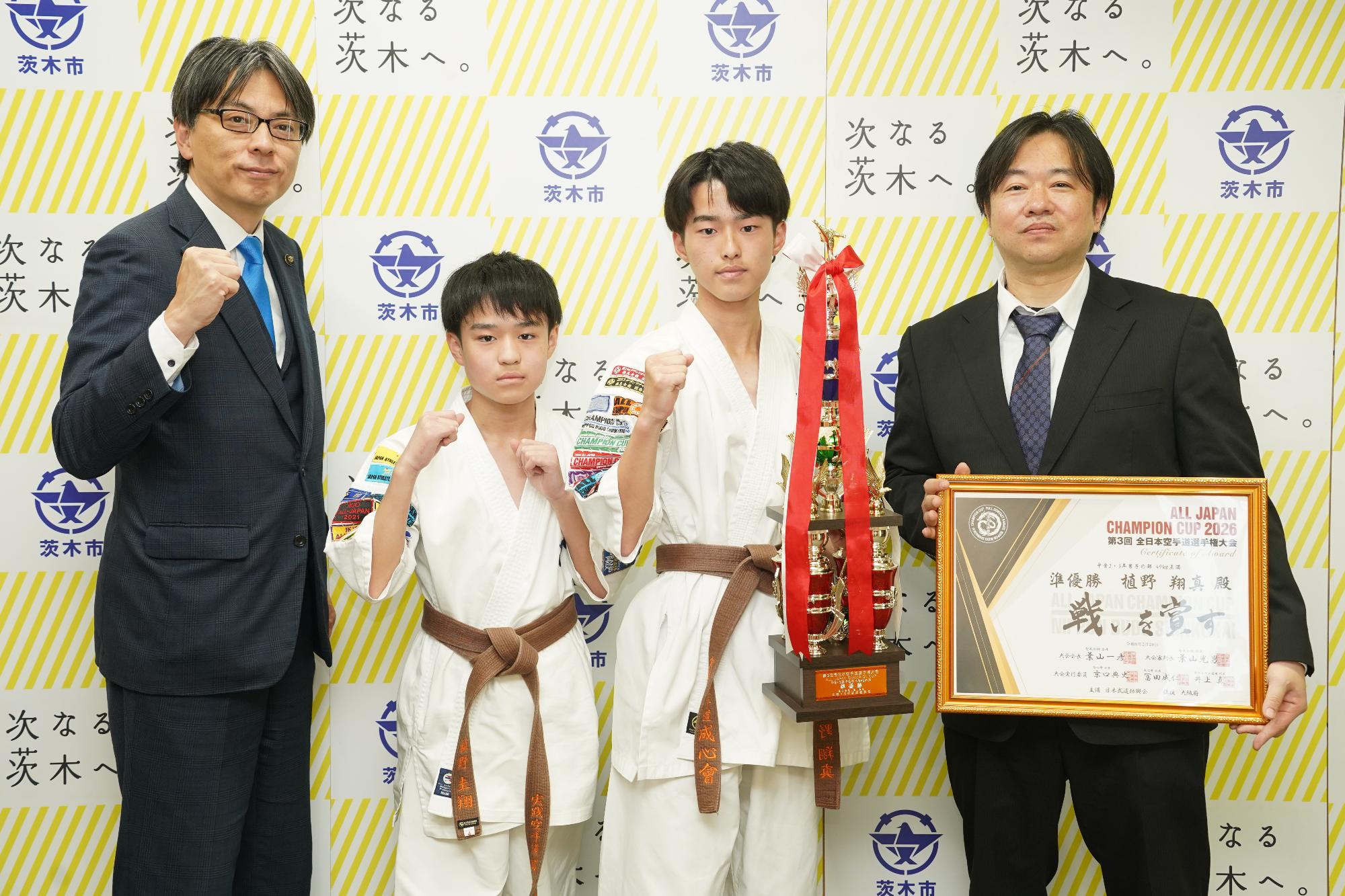 ガッツポーズをする選手、関係者と市長の写真