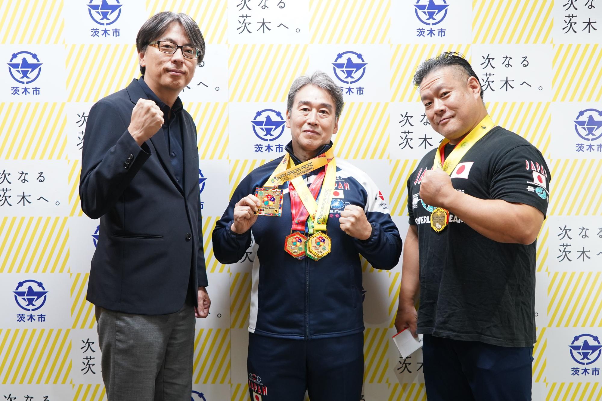 ガッツポーズをする選手2名と市長の写真