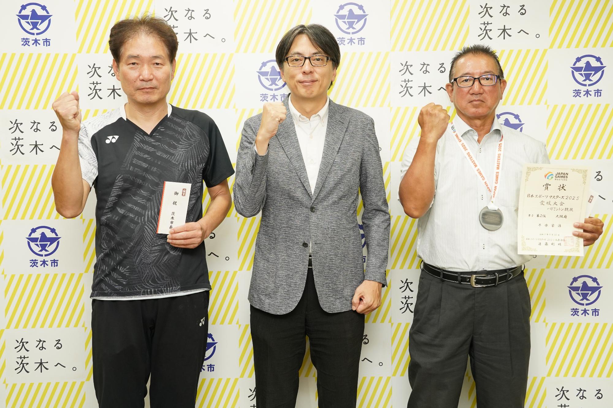 ガッツポーズをする選手2名と市長の写真