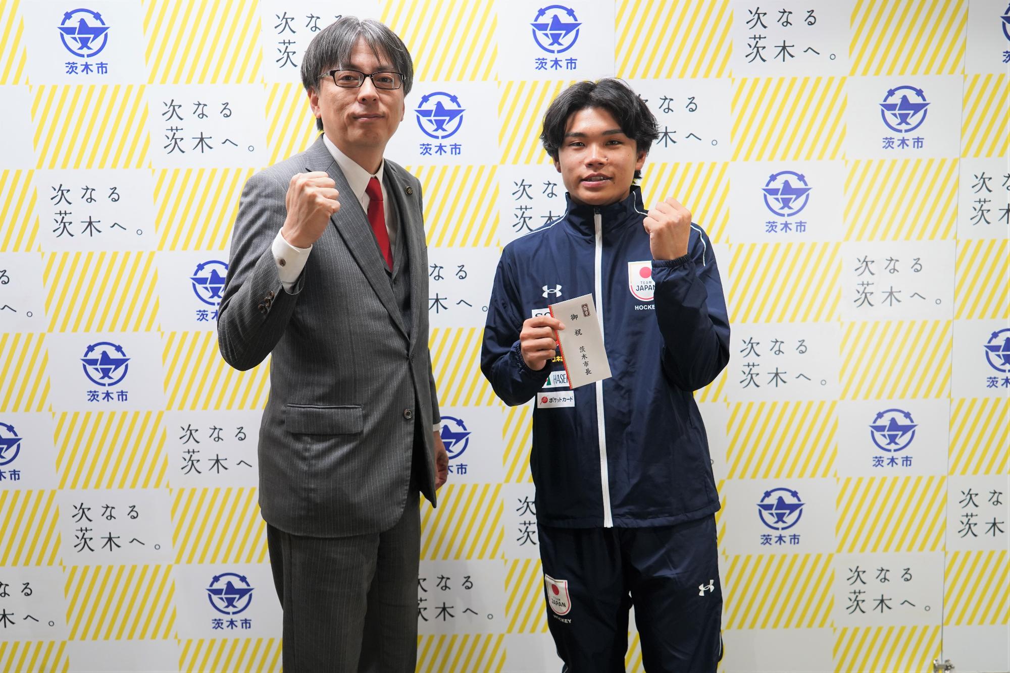 ガッツポーズをする選手と市長の写真