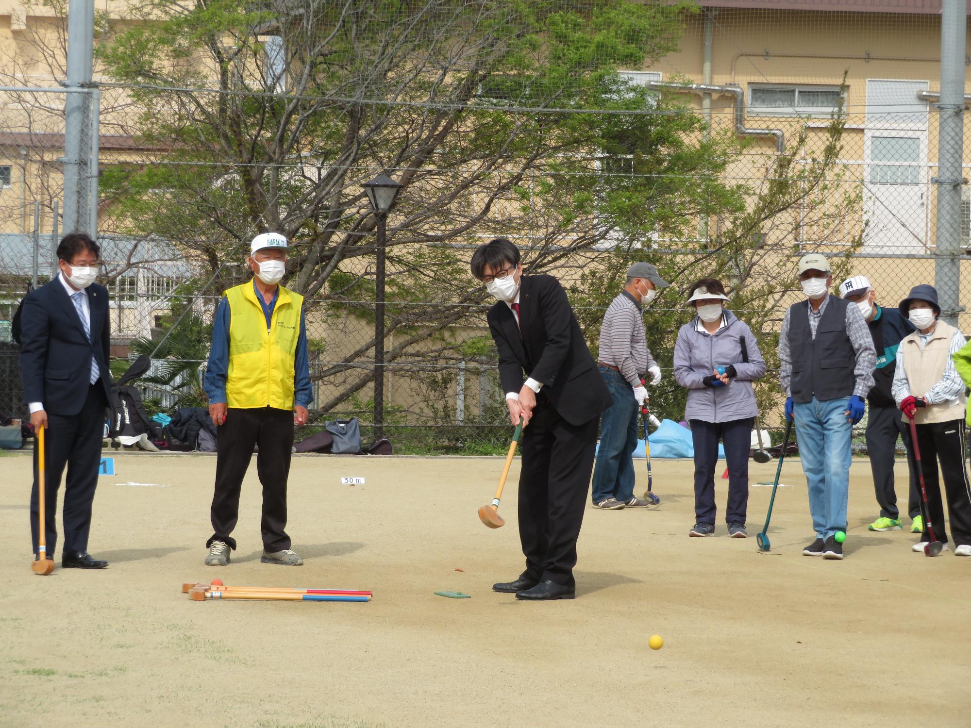 参加者の皆さんが見守るなか始球式をする市長の写真