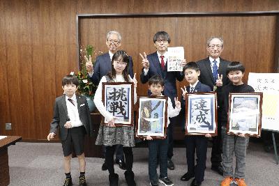 自身の作品の写真を持つ受賞者の皆さんと並ぶ市長の写真