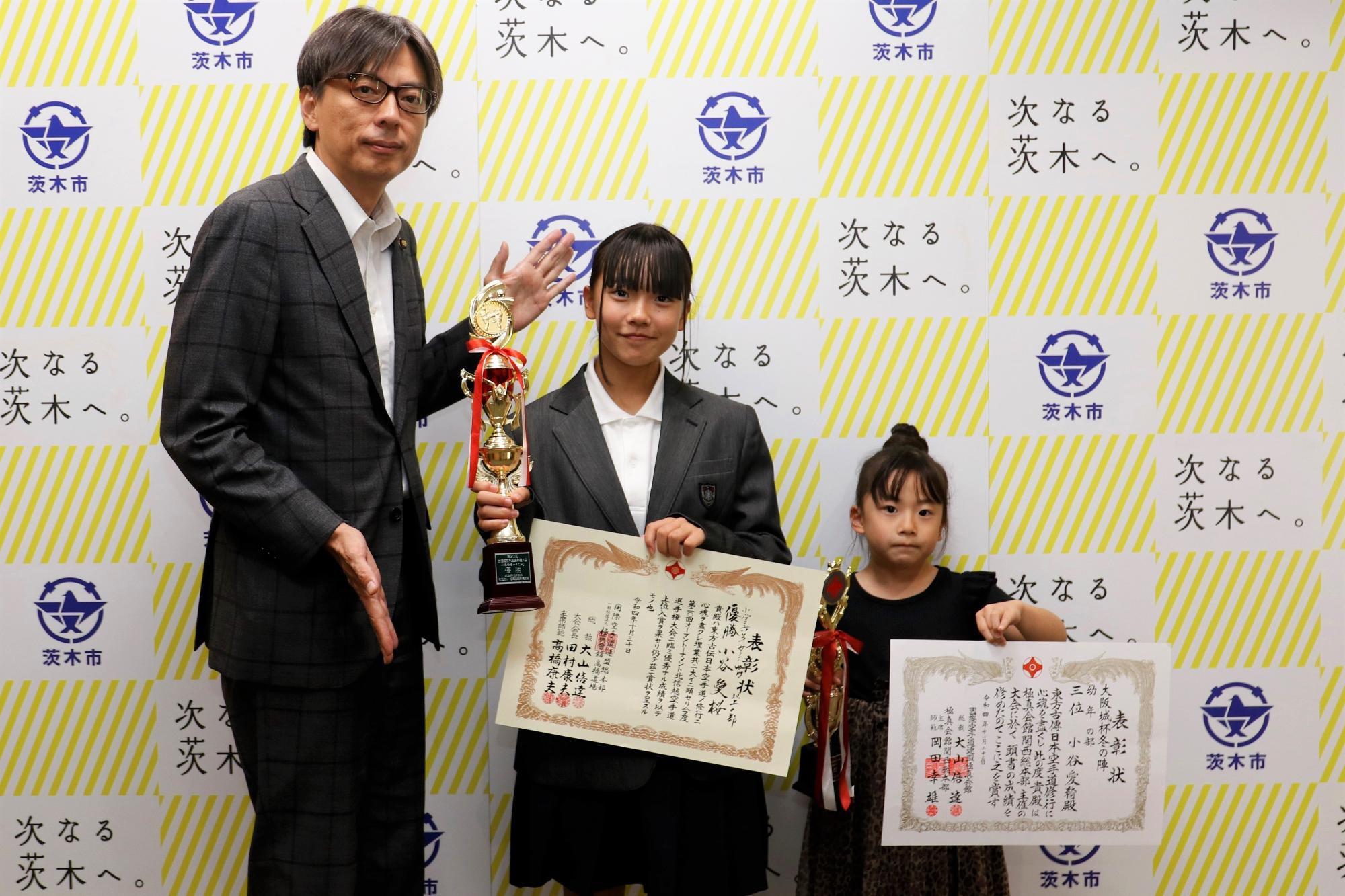 表彰状とトロフィーを持つ小谷愛桜さん・小谷愛綺さんと市長の写真