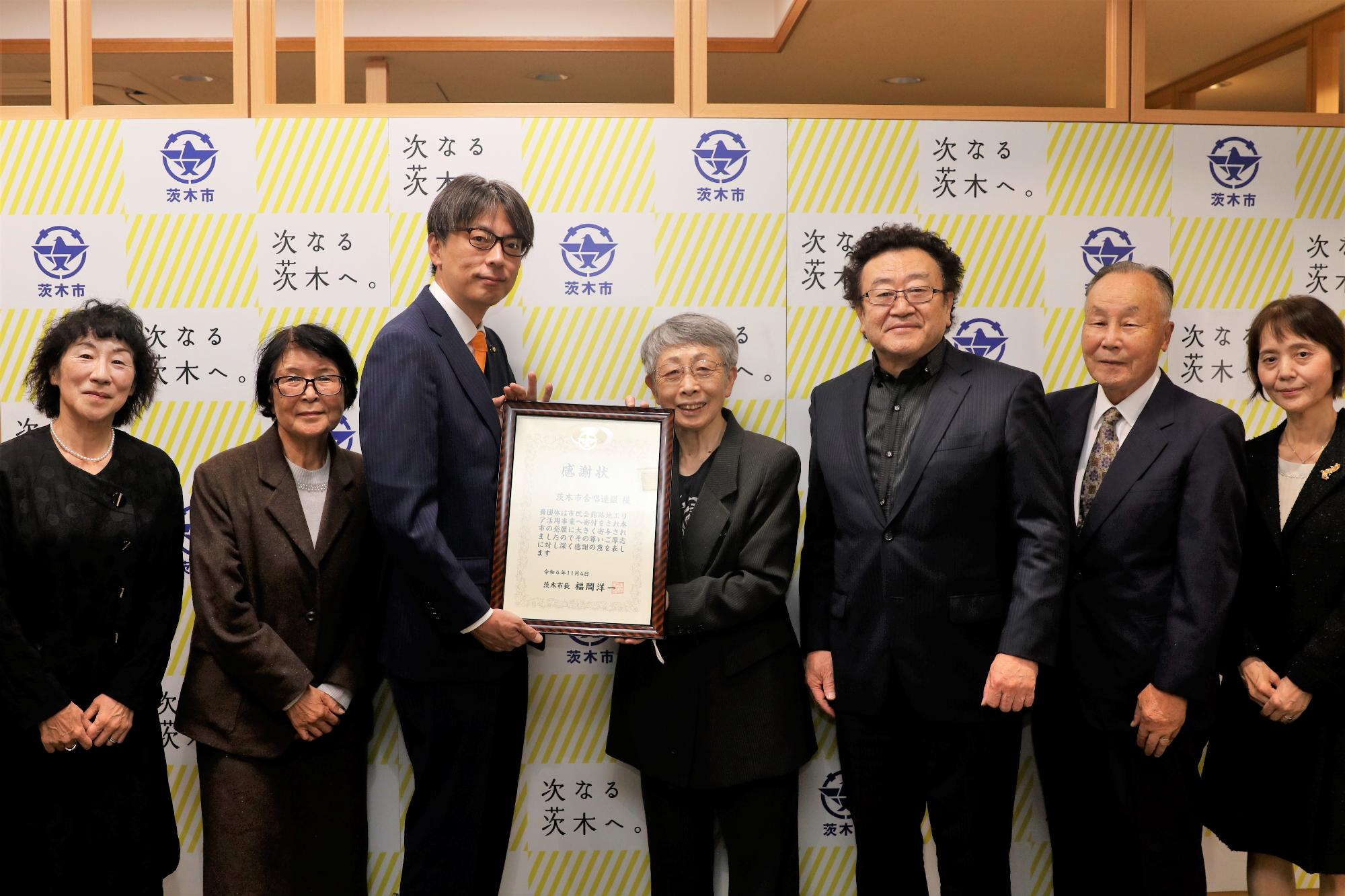 感謝状を持つ、茨木市合唱連盟の皆さんと市長の写真