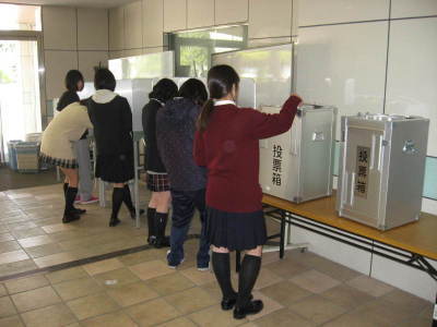 十さんの選挙で使う投票箱で生徒会の役員の投票を行う生徒達の写真