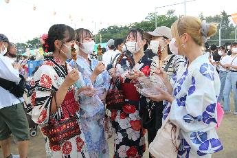 浴衣で焼き鳥を片手に談笑している様子