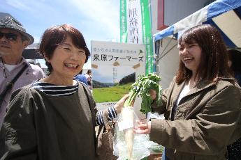 地元の農産物を買う笑顔の女性