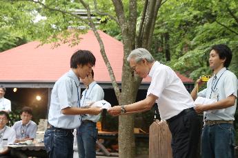 キャンプカウンセラーが岡田教育長より帽子を受け取っている様子