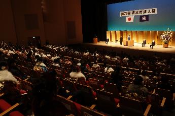 隣と間隔を空けて座り、市長のあいさつを聞いている様子