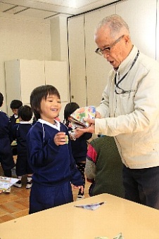 おじいさんから折り紙を教わる園児の写真