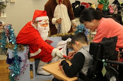車椅子の男の子にプレゼントを手渡すいばらきサンタの写真