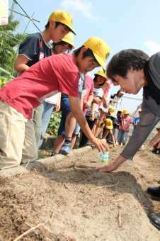 大豆の植え付けを体験している児童らを撮影した画像