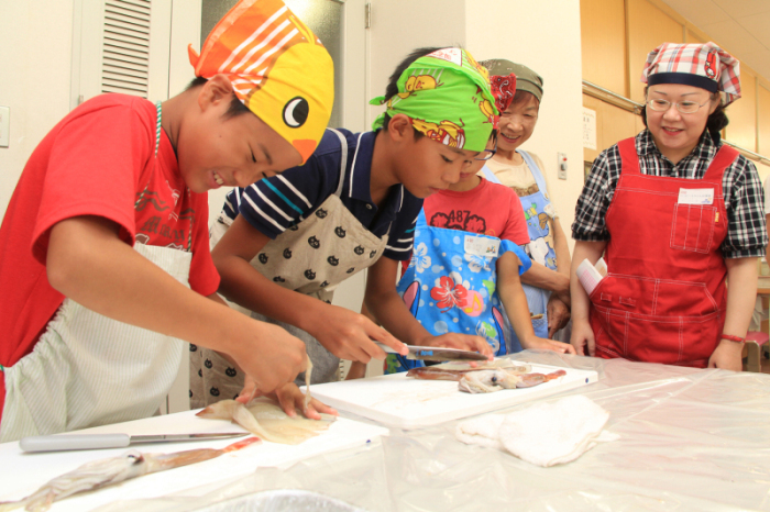 魚の調理に挑戦する子ども達を撮影した画像