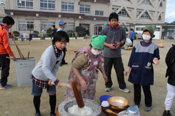 杵を持ち餅つきをする児童の写真